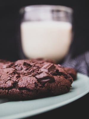 Vegane Schoko-Cookies auf einem Teller vor einem Glas Milch